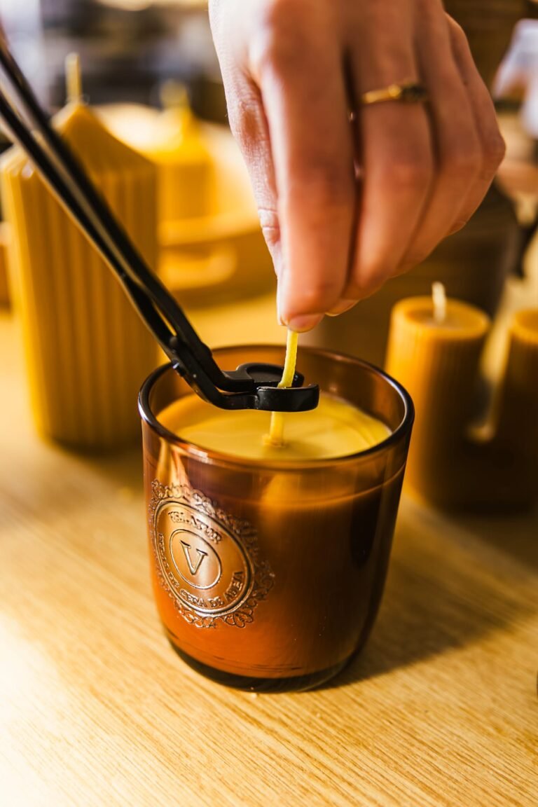 Inicio Mano recortando la mecha de una vela de cera de abeja en vaso ámbar con un cortamechas