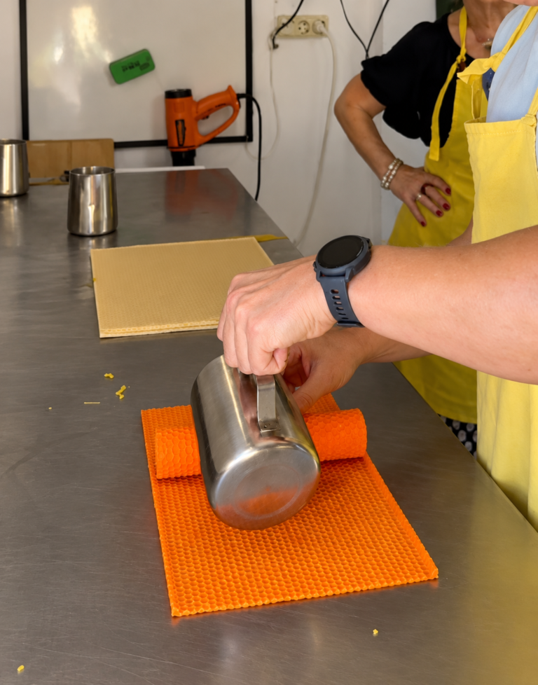 Inicio Enrollando una lámina de cera de abeja naranja para hacer una vela de panal en el taller